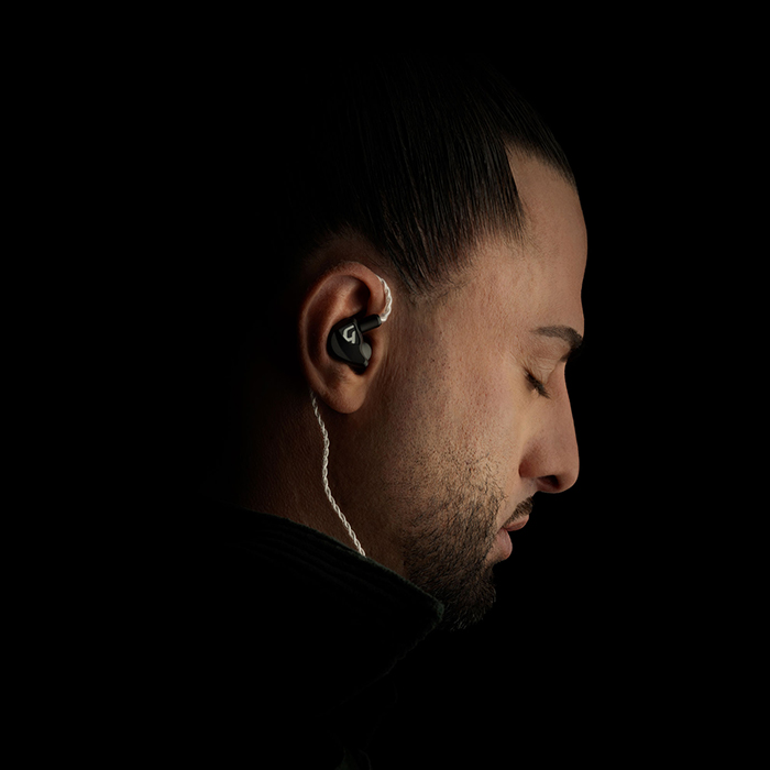 Audio enthusiast enjoying favorite songs with eyes closed, deeply engaged, while using Nair in-ear headphones for an improved listening experience.