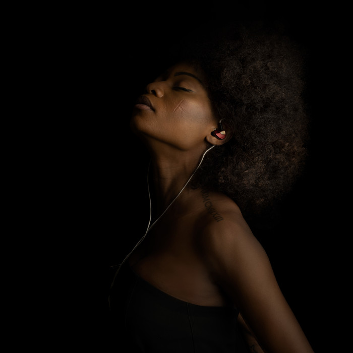 Young woman with closed eyes, deeply absorbed in listening to her favorite songs using Todi in-ear monitors for a superior audio experience.