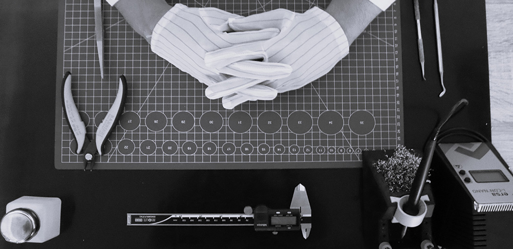 Top view of a workstation displaying tools used in the Gaudiolabs production process, including a caliper, soldering iron, pliers, and isopropyl alcohol.