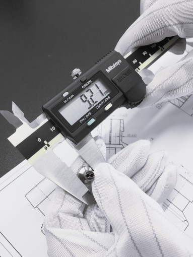Measurement phase using a caliper on an aluminum nozzle with a technical drawing in the background. Image emphasizing precision and attention to detail in the manufacturing Gaudiolabs process.